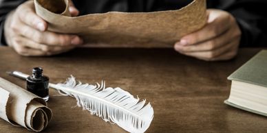 a feather, ink bottle and book on the table 