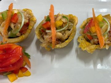 Three colorful appetizer cups filled with vegetables and chicken, garnished with carrot sticks.
