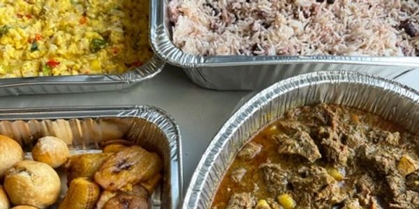 Aluminum trays filled with Caribbean dishes including rice, stew, fried plantains, and dumplings.