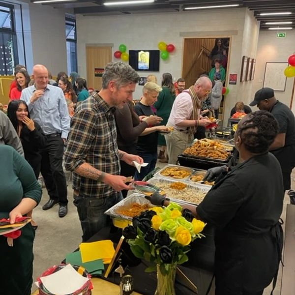 People serving and enjoying food at a buffet in a festive indoor setting.