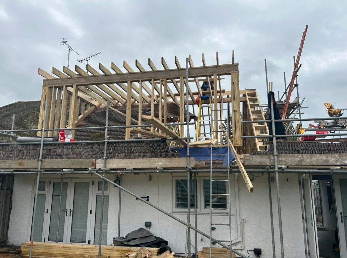 Wooden framework under construction on a house roof with scaffolding.