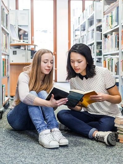 Two high school girls researching at a library