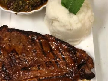 Grilled steak served with a side of mashed potatoes and sauce.