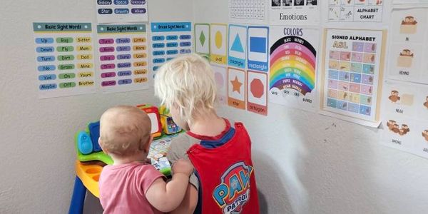 Two young children playing and learning at a colorful educational table.