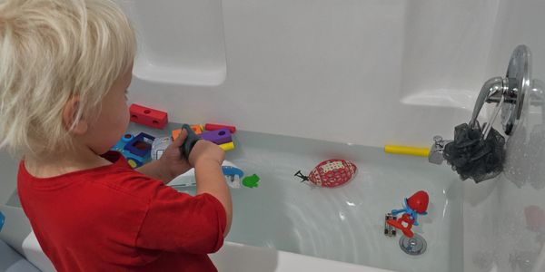 A young child playing with toys in a bathtub filled with water.