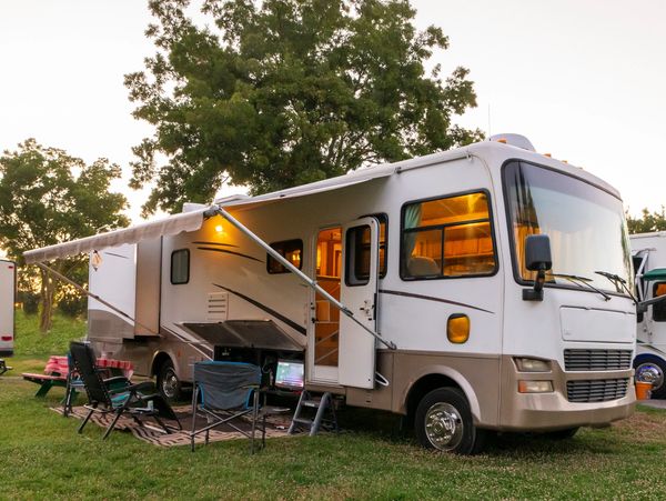 RV parked at a campsite with people sitting outside.