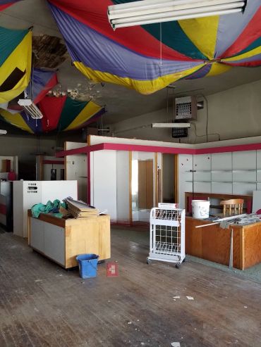 Empty room with colorful fabric ceiling and scattered furniture.