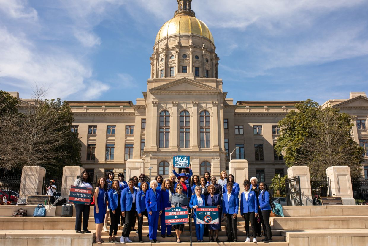 Group of people protesting voting rights outside a government building.