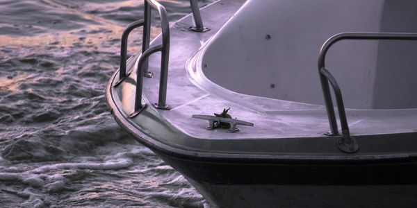 Close-up of a boat's bow on wavy water during sunset.