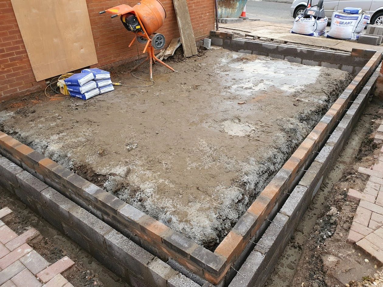 Construction site with brick foundation and cement mixer.