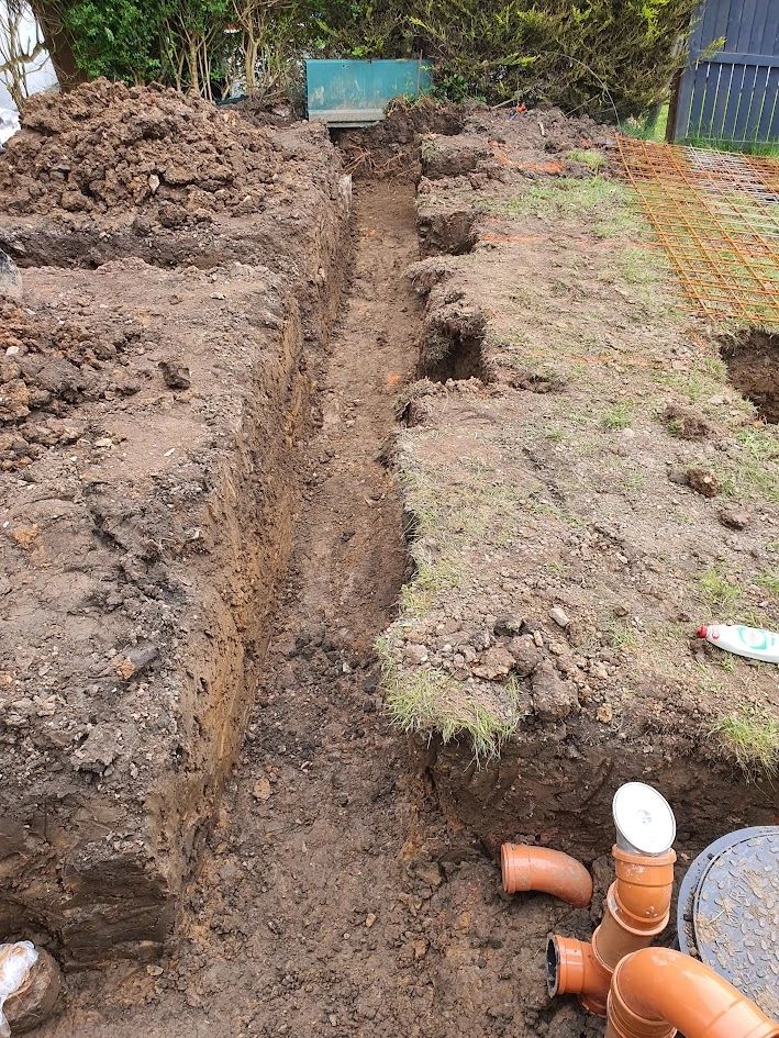 Deep trenches dug in soil for construction or plumbing work.