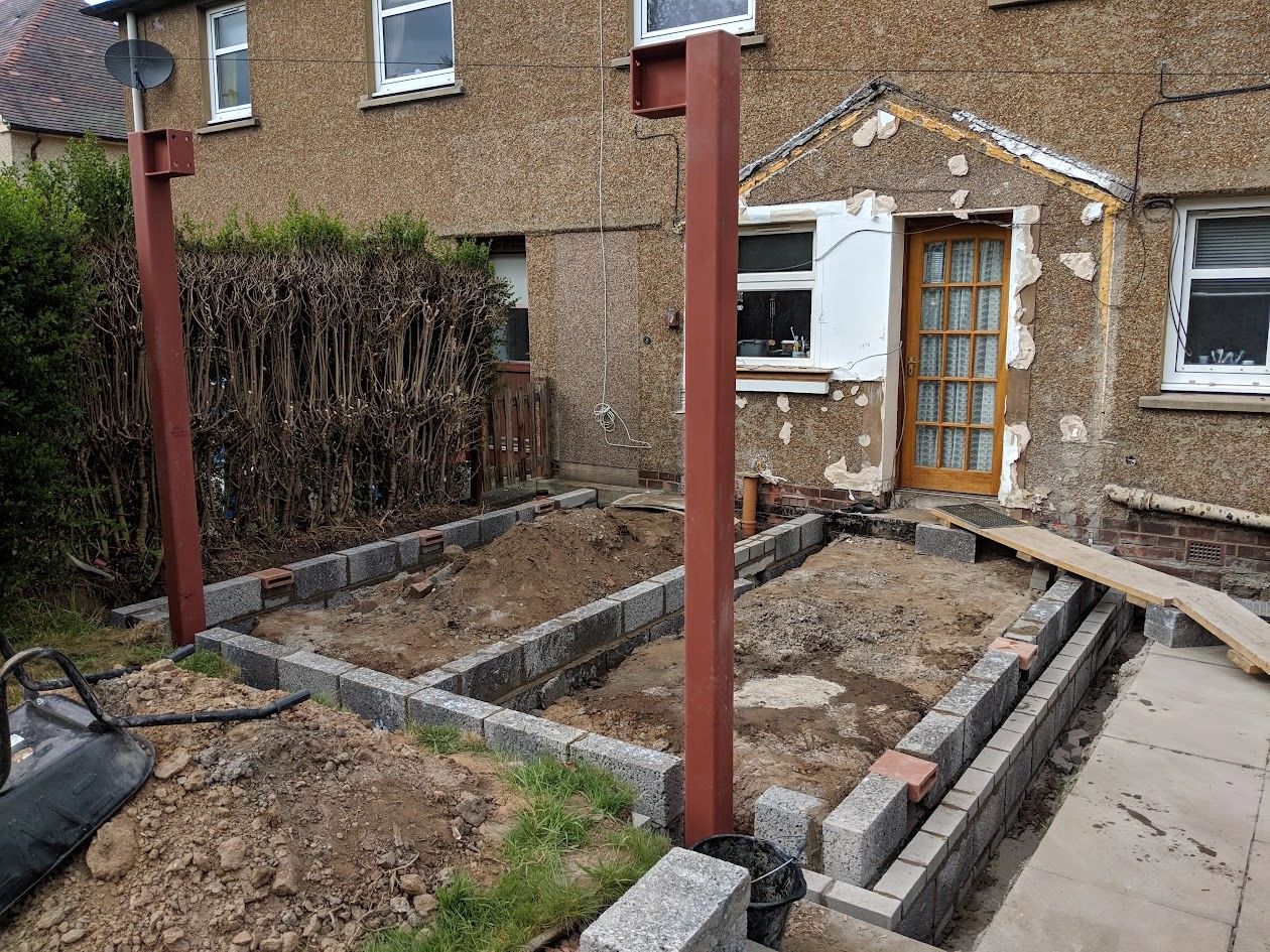 House extension under construction with foundation blocks and steel supports.