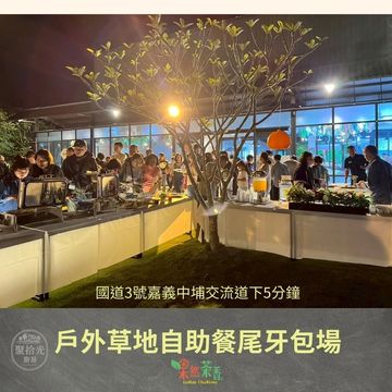 Outdoor buffet dinner with people gathered around food stations at night.