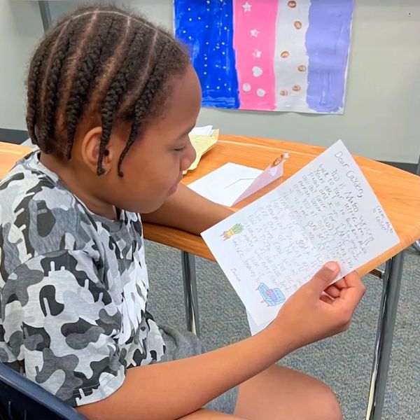 Student reading a letter from his Dearist pen pal.