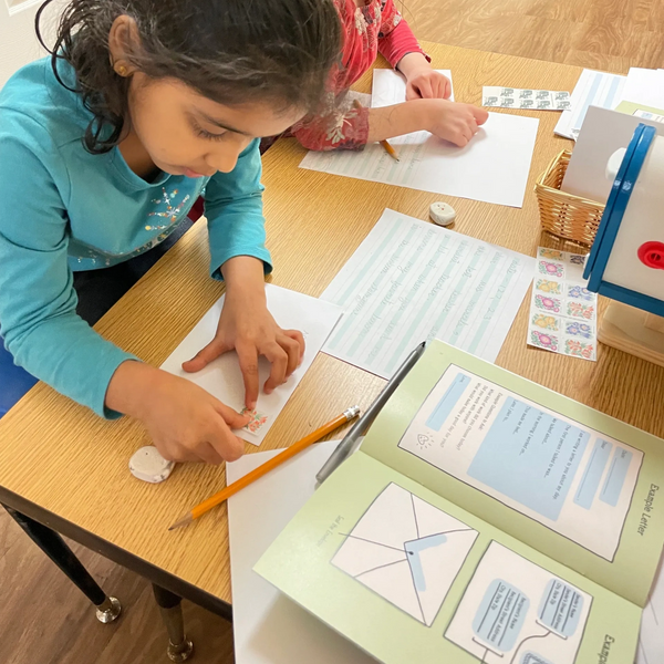 Students at desk placing stamps on envelopes