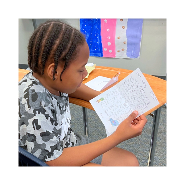 Student reading a letter from his Dearist pen pal.