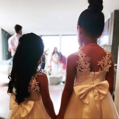 Two young girls in elegant dresses holding hands at a formal event.