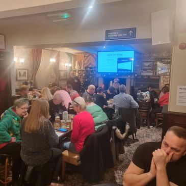 Group of people watching a presentation in a cozy pub.