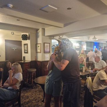Two people hugging in a crowded pub.