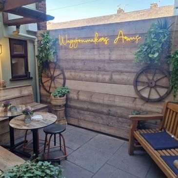 Cozy outdoor seating area with rustic decor and neon sign.
