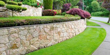 A stone retaining wall with sod and landscaping