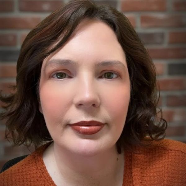 Close-up portrait of a woman with short brown hair and warm makeup.
