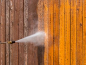 Pressure washing a wooden fence to clean and restore its appearance.