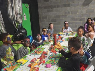 Children with face paint enjoying a birthday party with snacks and decorations.