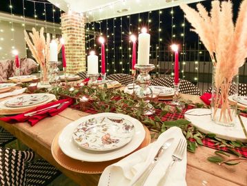 Cozy holiday table setting with candles, floral plates, and festive decorations.