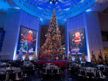 A grand Christmas tree with festive decorations and lights in a large hall.