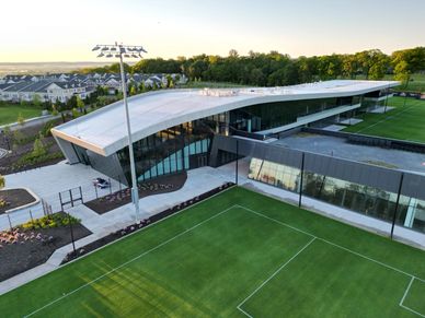 Modern sports facility with a soccer field and curved roof building.