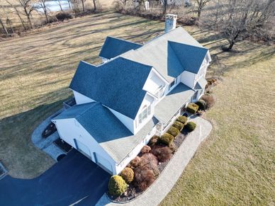 Large suburban house with a gray roof and manicured lawn.