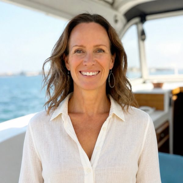 Smiling woman with wavy hair on a boat near the water.