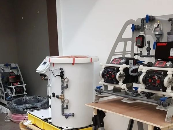 Industrial chemical feed systems with pumps and gauges in a workshop setting.