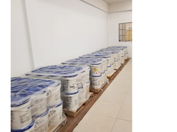 Rows of plastic-wrapped paint buckets with blue lids on pallets.