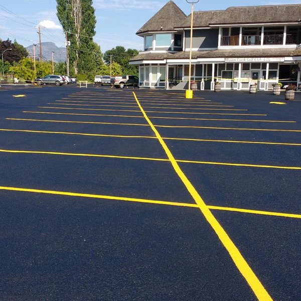 Empty parking lot with bright yellow lines outside a golf club building.