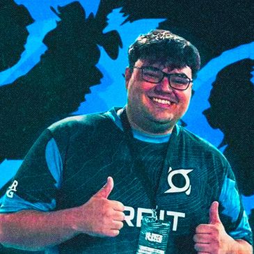 Smiling man giving thumbs up wearing a gaming jersey at an event.