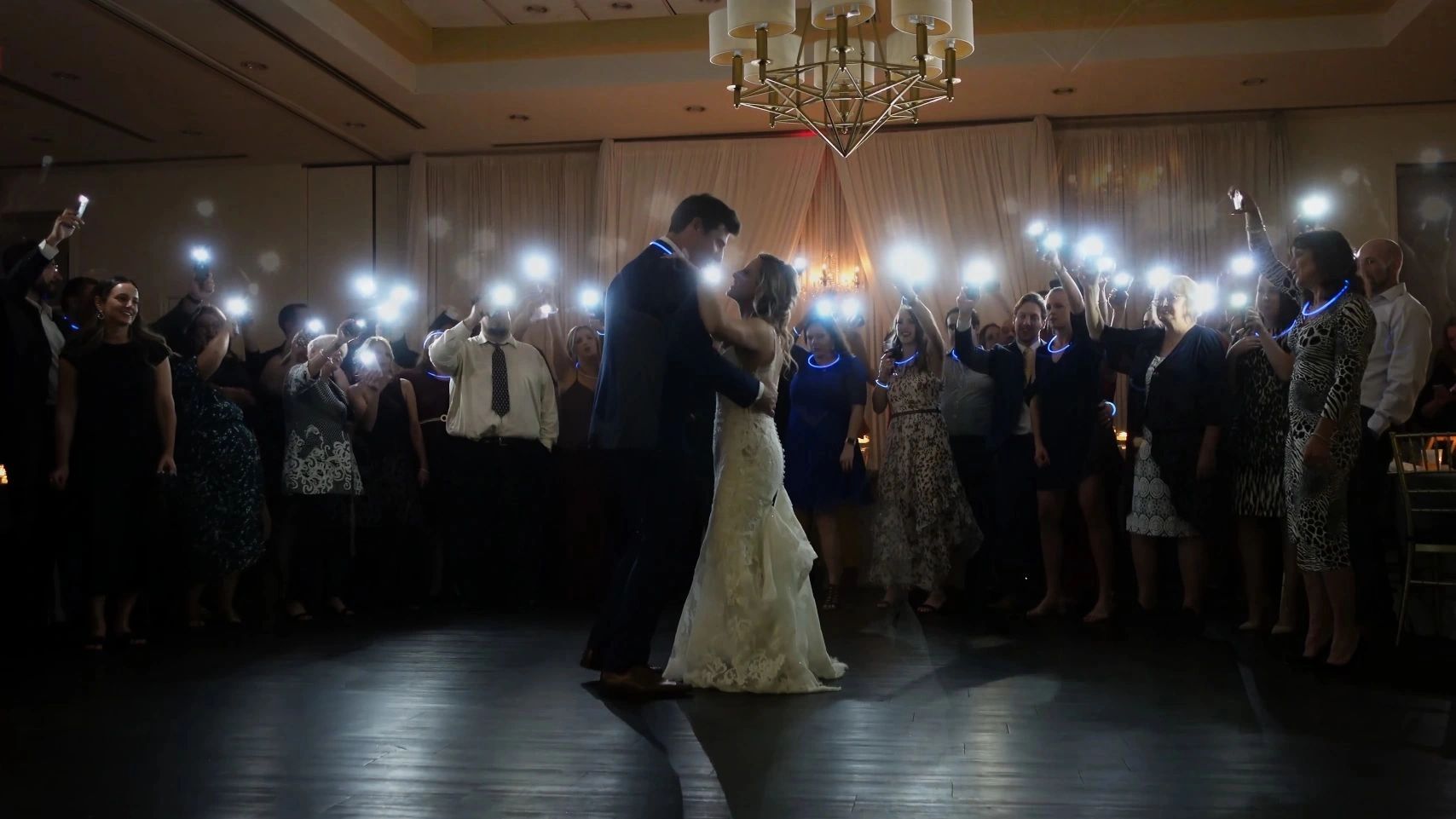 Bride and groom share a dance surrounded by guests holding up lights.