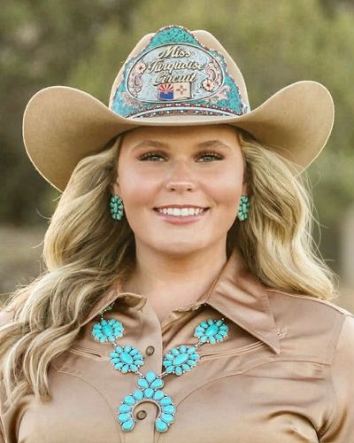 Smiling woman in a cowboy hat and turquoise jewelry.
