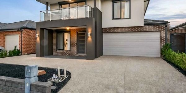 Modern two-story house with large driveway and balcony.