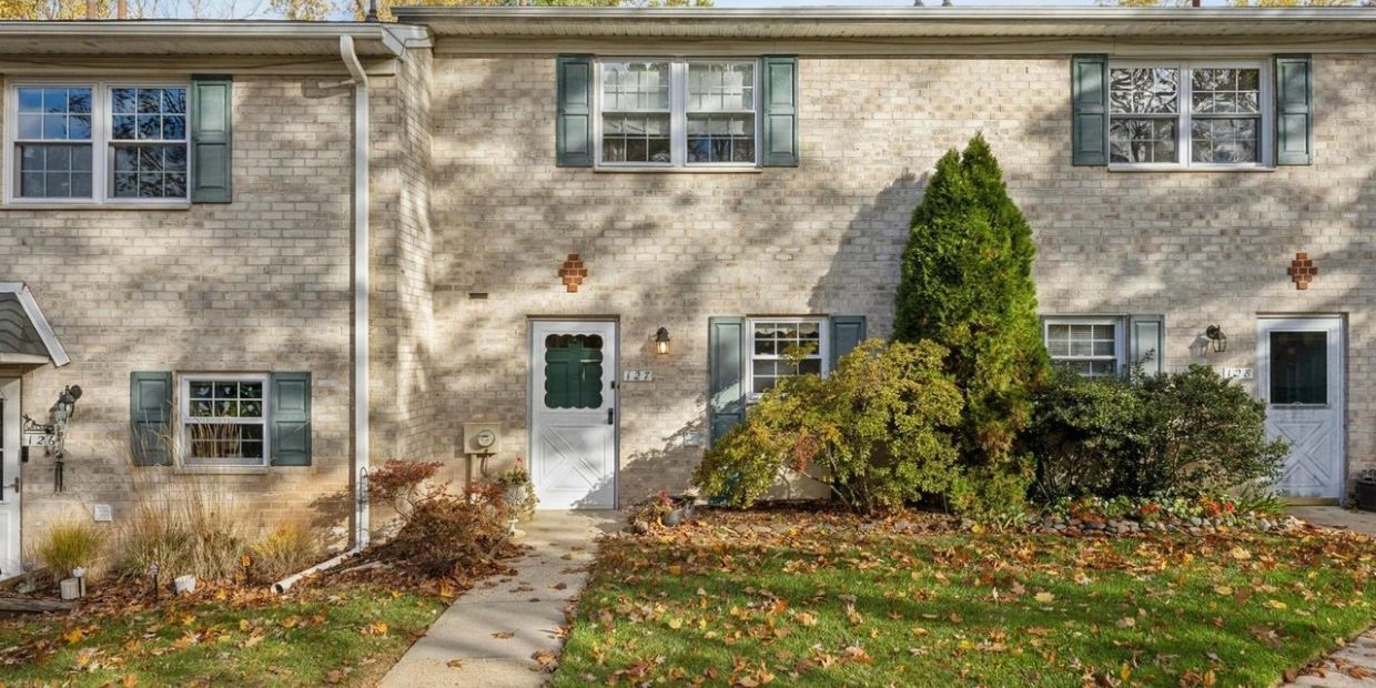 Brick townhouse with green shutters and autumn foliage.