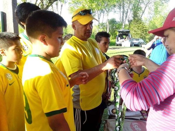 Youth soccer team receiving medals and awards outdoors after a match.