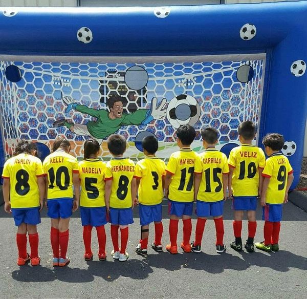 Children in soccer jerseys stand facing a soccer goal backdrop with a goalkeeper illustration.