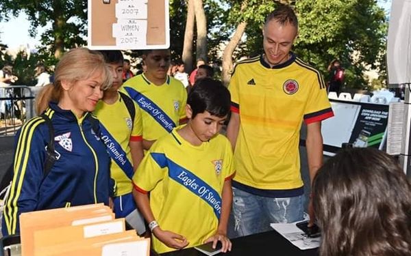 Woman helping child register for soccer league with parent nearby