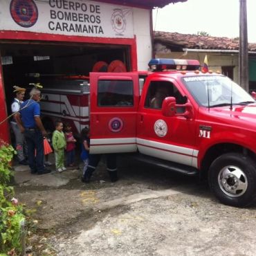 Children and adults visiting a fire station with a red fire truck.