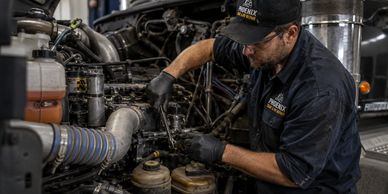 Mechanic working on a truck engine with tools in a garage.