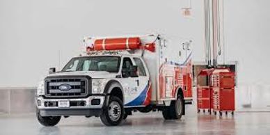A white utility truck with red and blue markings inside a large garage.