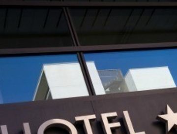 Reflection of a building on a glass surface above hotel signage.