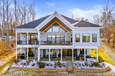 Custom home exterior showing walk-out basement patio, upper deck, and exterior spiral staircase