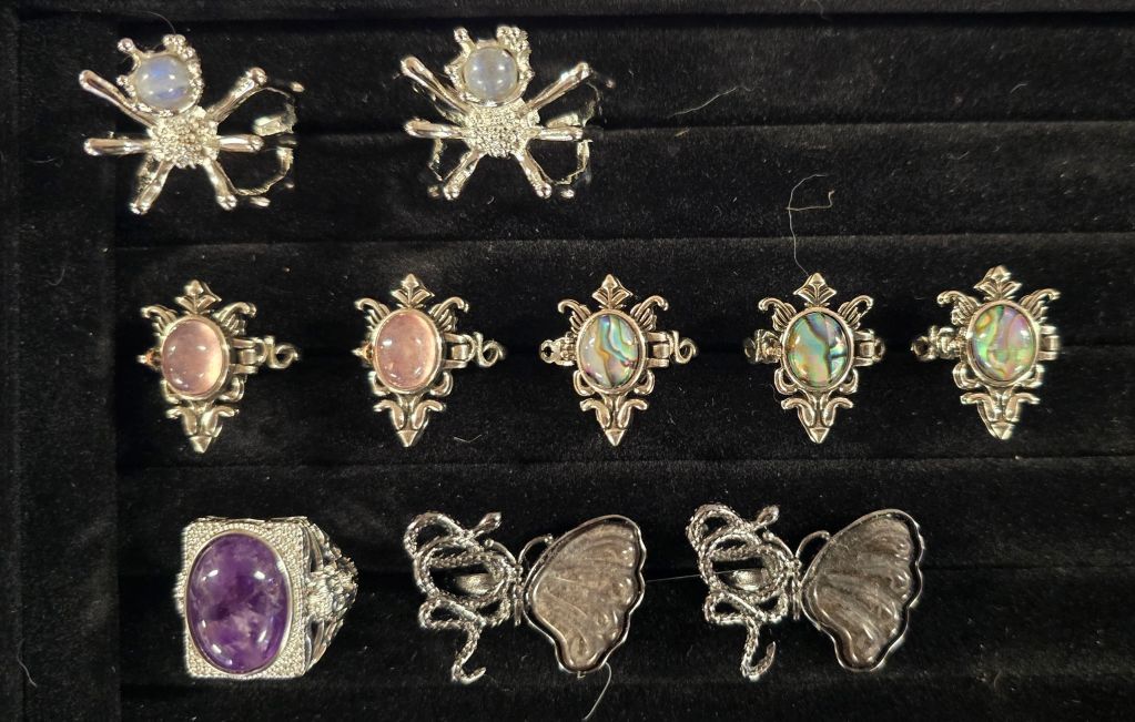 Collection of ornate silver rings with various gemstones on black velvet.
